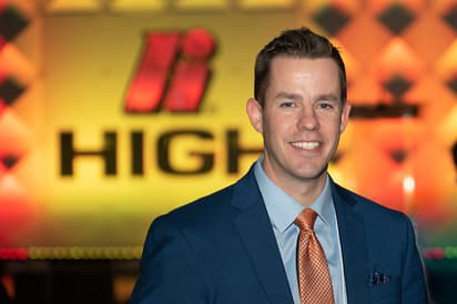 John McCormick stands in front of the stage at the High Forum with a giant High logo in the background.